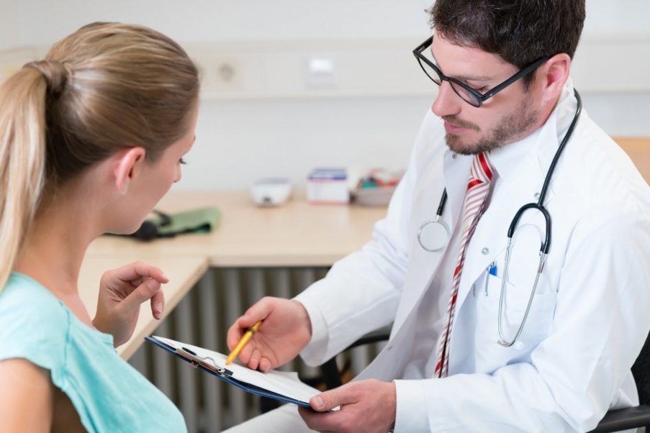 en consulta, un doctor comenta con una paciente el informe que sostiene en sus manos.