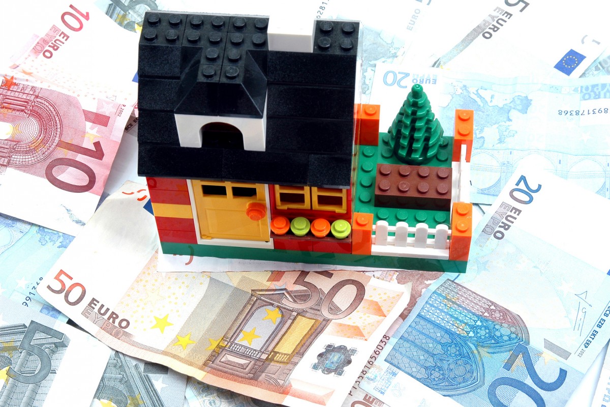 casitas rojas de lego sobre billetes de 100 euros subrogación hipotecaria